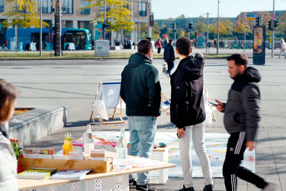 Zwei Menschen auf einem Platz, die den Platz beobachten und über Stadtgestaltung sprechen.